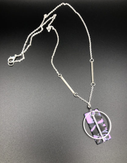 purple and black rectangle with silver circle and bar charm
